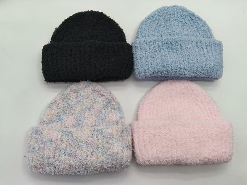 Four fluffy knit beanies laid flat in black, light blue, pastel tie-dye, and soft pink colorways on white background - no MOQ for stock designs