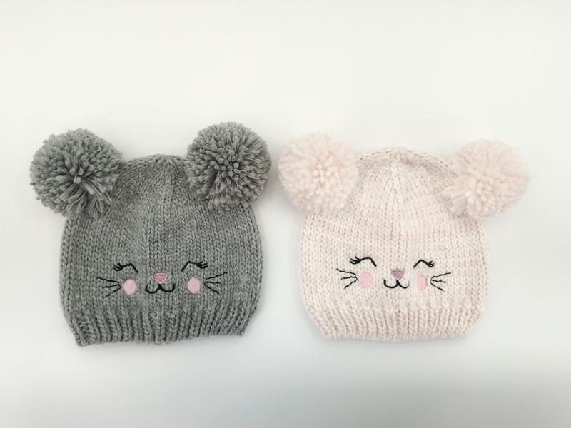 Two knitted baby beanies with pom-pom ears and embroidered cat faces, one gray and one light pink, on white background - bulk order 500+ pcs extra 8% off