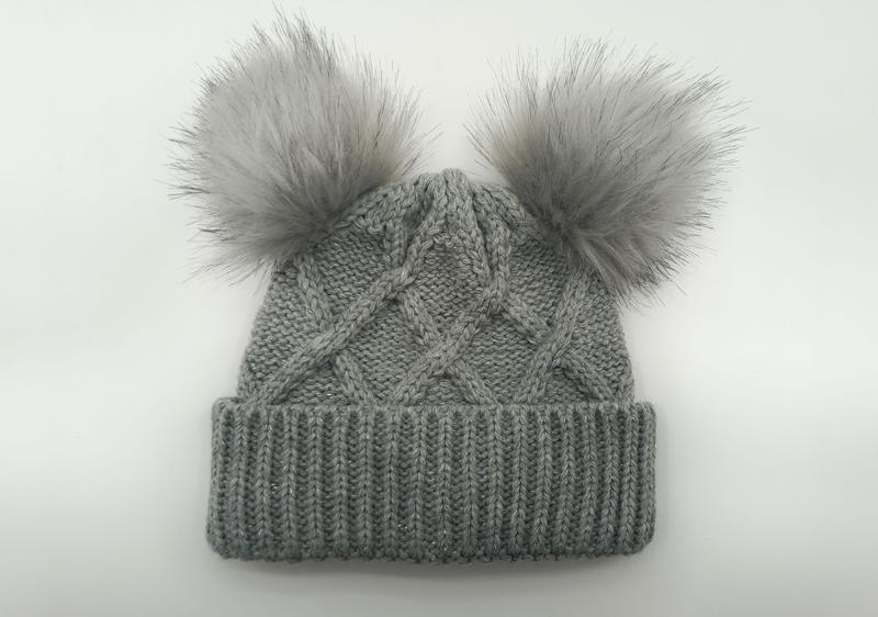 Gray cable knit winter beanie hat with two fluffy faux fur pom poms on top, ribbed cuff, flat lay on white background - bulk order 500+ pcs extra 8% off