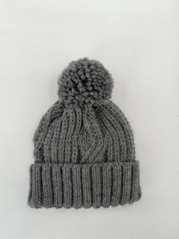 Grey chunky cable knit winter beanie hat with large pom pom and ribbed cuff, flat lay on white background - factory direct price no middleman