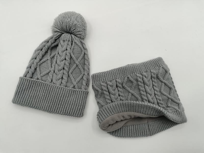 Grey cable knit winter beanie hat with pom pom and matching fleece-lined neck gaiter set on white background - event merchandise supplier