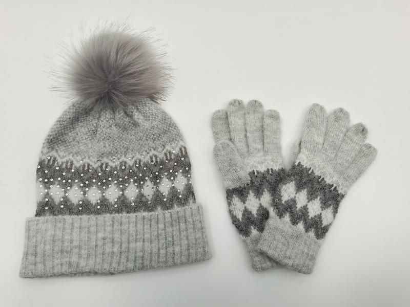 Grey knitted Fair Isle beanie hat with fur pom-pom and pearl embellishments alongside matching knit gloves set - hotel amenity scarf supplier