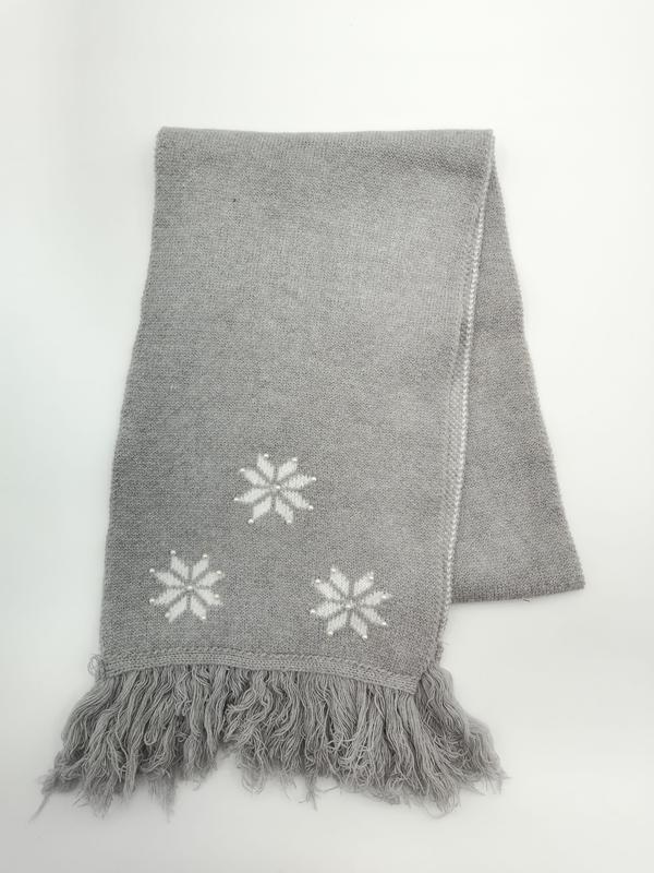 Folded grey knitted throw blanket with white intarsia snowflake motifs and fringe trim on white background - no MOQ for stock designs