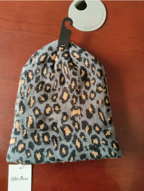 Grey and black leopard animal print knit beanie hat with tan spots, displayed on retail hanger with tag - ask bulk pricing get discount
