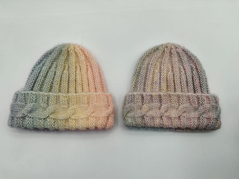 Two hand-knitted pastel variegated beanies with cable cuff detail, one in green-yellow-peach and one in muted pink-taupe tones - corporate gift customization