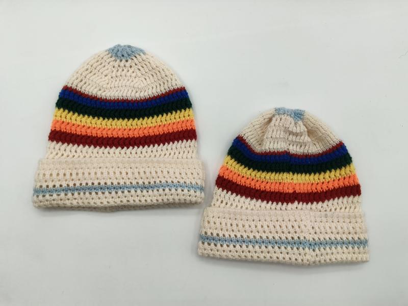Two cream crochet beanies with rainbow stripes in blue, green, yellow, orange, red and light blue pom-top detail - factory direct price no middleman
