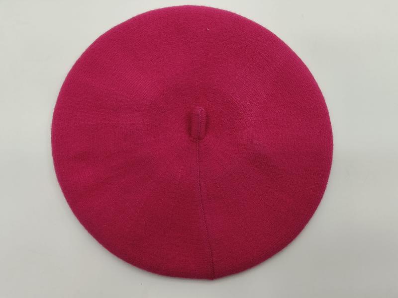 Flat lay of a hot pink fine knit wool beret with center button top on white background - hotel amenity scarf supplier