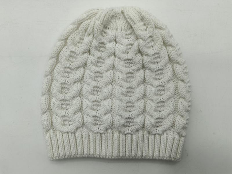 White cable knit winter beanie hat with bubble pattern texture and ribbed cuff, laid flat on light background - boutique retail bulk order