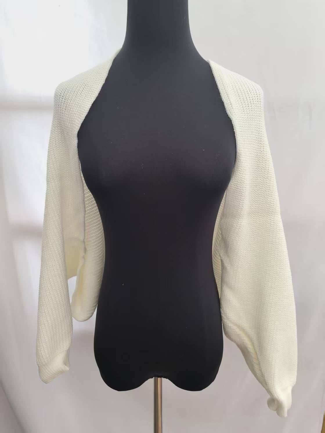 Cream chunky knit open front bolero shrug with long sleeves displayed on a black dress mannequin against white background - WhatsApp quote in 2 hours
