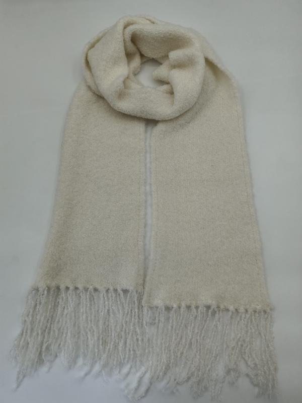 Ivory cream boucle wool blend scarf with fringe ends, looped and laid flat on white background - OEM custom logo accepted The boucle yarn construction is the defining feature of this product. Unlike smooth-spun or standard-plied yarns, boucle is created by feeding one yarn at a faster rate than its core thread during spinning, producing a series of tiny loops along the fiber's surface. When knitted into a scarf, these loops create a richly dimensional, almost cloud-like texture that catches light unevenly — producing the kind of visual depth that flat-knit scarves simply cannot replicate in product photography. The wool-blend composition adds natural warmth, breathability, and the subtle lanolin softness that consumers associate with quality wool accessories, while the acrylic component in the blend ensures durability, shape retention, and easy-care properties that make the scarf retail-ready for consumers who want luxury without dry-clean-only maintenance requirements. The ivory cream colorway is a warm-neutral that coordinates seamlessly with the full spectrum of winter outerwear — from black and navy wool coats to camel and beige trenches to olive and burgundy puffers — making it one of the most versatile single-SKU scarf investments a retailer can make. Manufacturing takes place in our BSCI-certified facility, where social compliance auditing covers fair wages, regulated working hours, and safe factory conditions — documentation we provide during vendor onboarding to satisfy the ethical sourcing requirements that European and North American retailers now mandate as standard procurement practice. The yarn itself is OEKO-TEX Standard 100 certified, meaning every fiber has been independently tested and verified free from harmful substances. This dual-certification package is particularly important for boucle products because the textured surface increases total fiber surface area, making independent safety verification more valuable to consumers who may have skin sensitivities or who prioritize certified-safe textiles for themselves and their families. Our factory's triple-inspection protocol — inline boucle-consistency monitoring during knitting, post-finish texture QC, and AQL 2.5 final random-sampling audit — ensures that the signature looped texture is uniform across every unit in a production run, from 100 pieces to 50,000. On the wholesale procurement side, this boucle scarf is available with an MOQ of 100 pieces per colorway, making it accessible for premium boutiques and curated online stores testing a new texture category while offering volume pricing at 500, 1,000, and 5,000+ unit tiers for established importers and department-store buyers. We support private label scarf programs with your own branded hangtag, woven label, care-instruction card, and retail-ready packaging — whether that is a simple polybag for value-oriented retail or a tissue-wrapped gift box for the premium segment. Our OEM scarf factory can also adjust the color: swap ivory cream for charcoal grey, blush pink, soft lavender, or any Pantone-matched shade that aligns with your seasonal color strategy. For buyers building a coordinated premium accessories collection, we can pair this boucle scarf with matching boucle beanies, fingerless gloves, and wrap scarves to create a texture-driven accessory program from a single certified supplier — a consolidation strategy that reduces freight costs and simplifies your QC and compliance documentation. From a retail sell-through perspective, boucle texture scarves occupy a unique position in the winter accessories market. They command a higher perceived value than standard knit scarves, which allows retailers to price them at a premium tier — typically supporting a 2.5x to 3x markup while delivering an accessible final shelf price to the consumer. The ivory cream colorway is deliberately chosen for maximum wardrobe versatility, which means lower return rates and broader demographic appeal across age groups and style preferences. Gift shops, resort boutiques, department-store accessory departments, premium online fashion platforms, and corporate gift programs all move significant volume of textured neutral scarves during the October-to-February gifting season. The boucle texture also photographs exceptionally well for e-commerce — the dimensional surface creates natural shadow and highlight variation that communicates quality and invites the kind of zoom-and-scroll engagement that correlates with higher conversion rates on product pages. Lead time on bulk production is typically 25 to 35 days following pre-production sample approval, which we ship within 7-10 business days of order confirmation. For buyers planning seasonal inventory, we recommend confirming specs by mid-July for September delivery to capture the full autumn-winter selling window. Our logistics team can arrange FOB, CIF, or DDP shipping terms depending on your preference, and we offer consolidation services for buyers sourcing multiple categories — scarves, beanies, gloves, and blankets — from our factory, reducing per-unit freight costs and streamlining import clearance documentation. We also recommend exploring our broader textured-scarf range, including our cable knit and ribbed knit collections, to build a comprehensive winter accessories assortment from a single certified manufacturer. Consolidating your sourcing with one BSCI-certified, OEKO-TEX-compliant supplier not only reduces logistics complexity but also strengthens your negotiating leverage on volume pricing — a compounding strategic advantage as your accessory program scales season after season. *Internal Links:* - Browse our complete [boucle scarf wholesale catalog](https://labubuskin.com/categories/scarves/) - Start a [custom boucle scarf OEM project](https://labubuskin.com/custom-scarves/) with your own label and color palette - 5-day digital sample ready