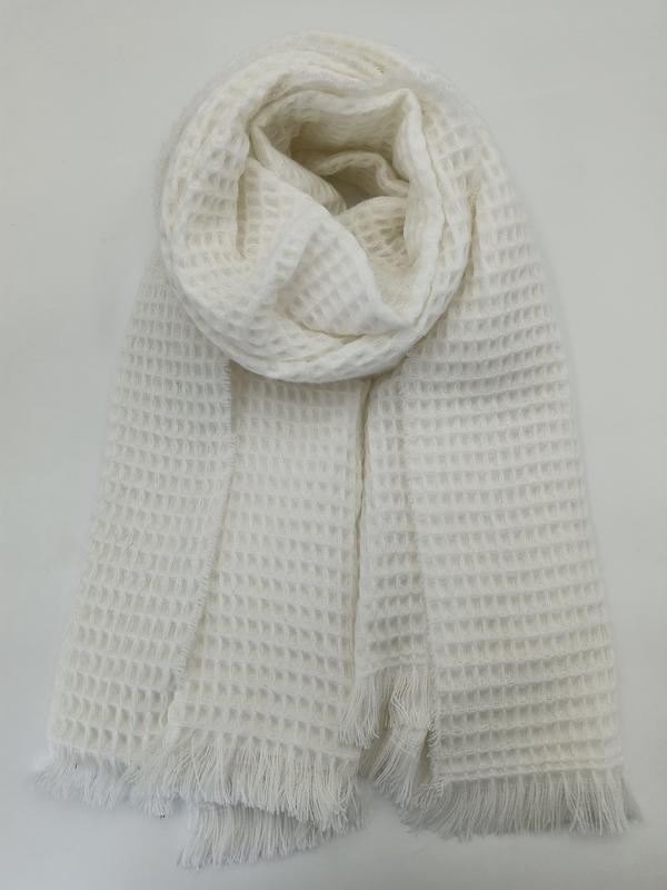 Ivory white waffle knit scarf with fringe ends, rolled and laid flat on white background showing textured grid pattern - hotel amenity scarf supplier