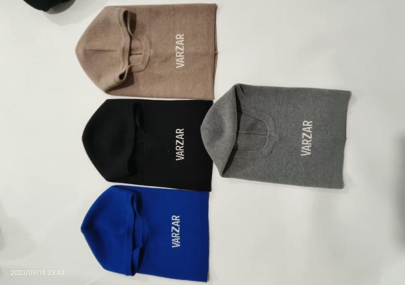 Four knit balaclava beanie hats in beige, black, gray, and blue laid flat on white surface with embroidered logo - jacquard custom pattern accepted