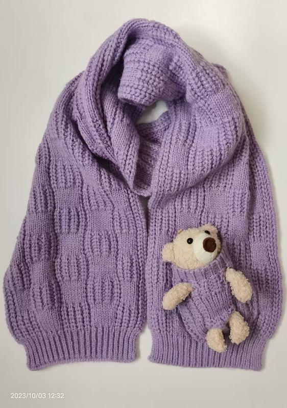 Lavender purple chunky knit oversized cardigan with wide shawl collar and small teddy bear stuffed in front pocket, flat lay view - corporate gift customization