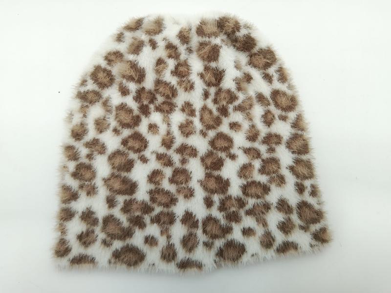 Soft white faux fur beanie hat with brown leopard print spots laid flat on white background - wholesale price for USA buyers
