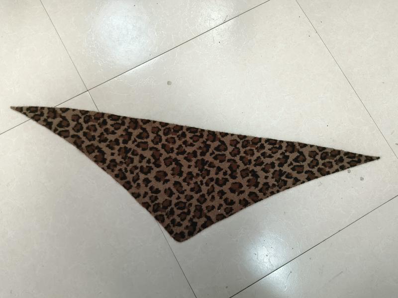 Triangular leopard print fabric bandana scarf with brown and black cheetah spots laid flat on white tile floor - hotel amenity scarf supplier