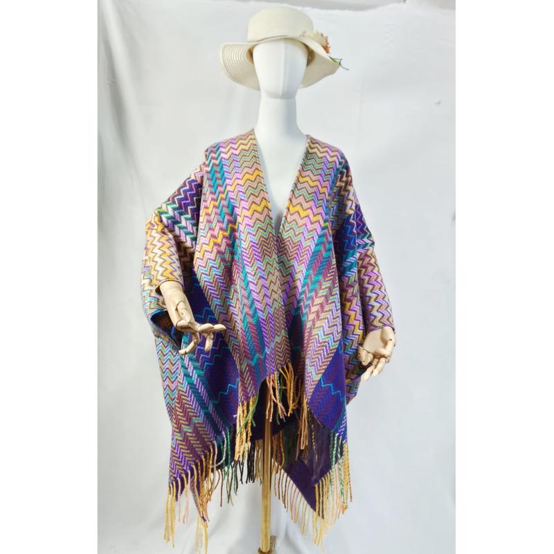 Mannequin wearing a multicolor chevron zigzag woven poncho wrap with long fringe trim and wide-brim hat - factory direct price no middleman
