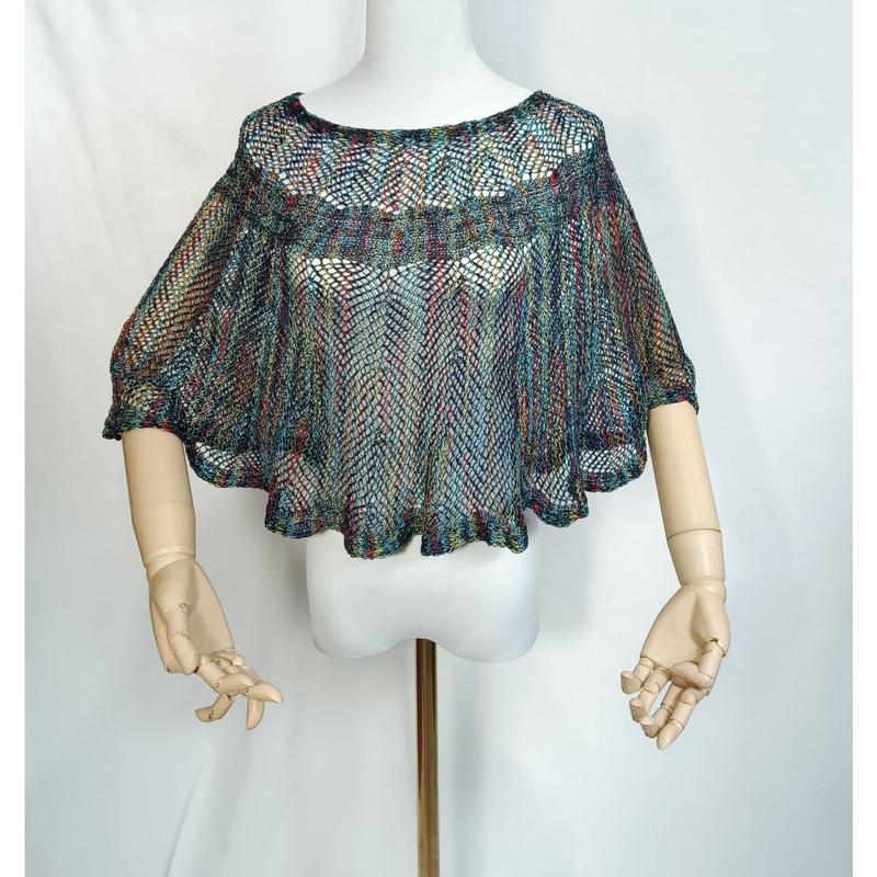 Multicolor open-weave knit crochet cape poncho displayed on mannequin with wooden articulated hands, bohemian mesh style - request quote reply same day