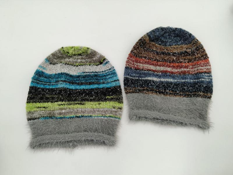 Two multicolor striped fuzzy knit beanie hats laid flat, one in blue-green tones and one in red-brown tones, both with gray fluffy cuffs - private label service available