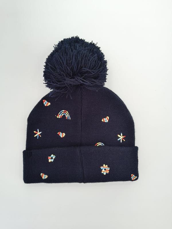 Navy blue ribbed knit winter beanie with large pom-pom and colorful embroidered rainbows, hearts, stars and flowers - private label service available
