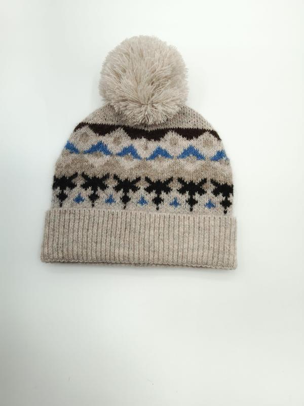 Oatmeal knit beanie hat with Fair Isle snowflake pattern in blue and black, topped with a fluffy cream pom-pom - retail buyer inquiry welcome - gift shop wholesale supplier