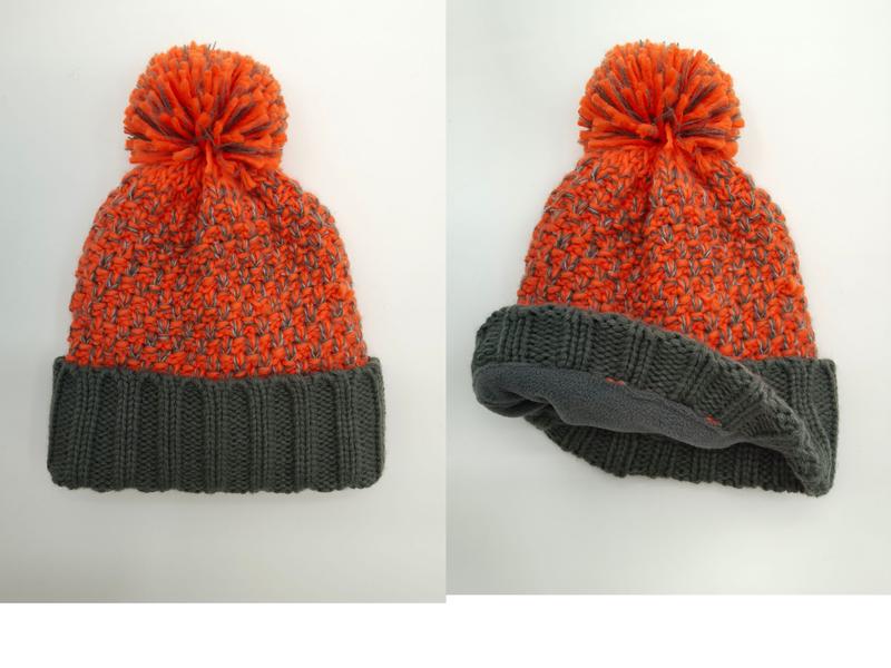 Orange and gray two-tone chunky knit winter beanie hat with large pom pom and folded gray ribbed cuff, fleece-lined interior shown - no MOQ for stock designs