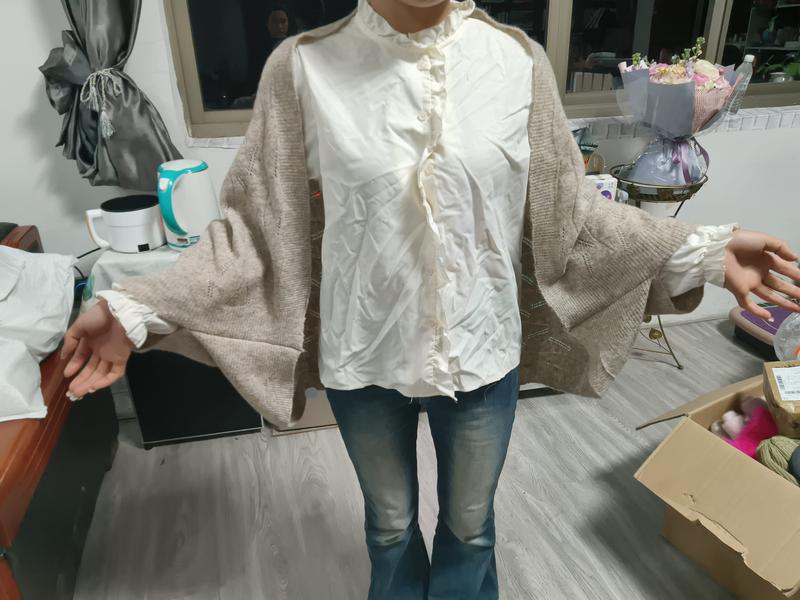 Woman wearing oversized beige knit cardigan layered over cream quilted ruffle-collar shirt with blue flare jeans indoors - bulk order 500+ pcs extra 8% off