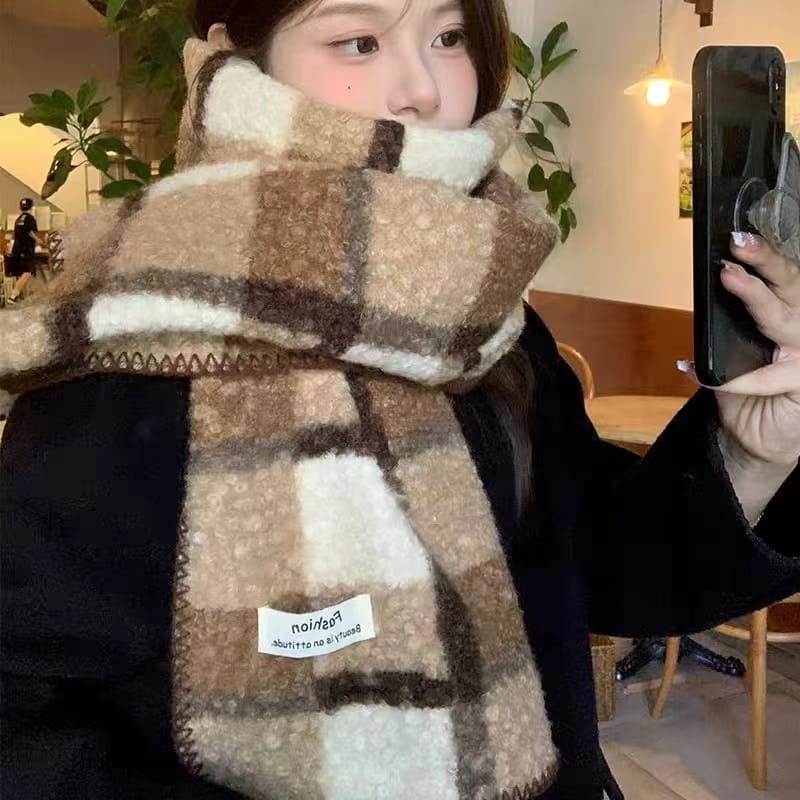 Young woman wearing a thick plaid fuzzy scarf in beige, brown and cream tones, taking a selfie indoors - custom logo label accepted
