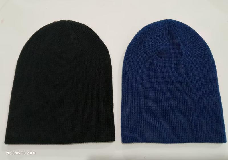 Two plain knit beanie hats laid flat, one black and one royal blue, showing ribbed texture and slouchy style - private label service available