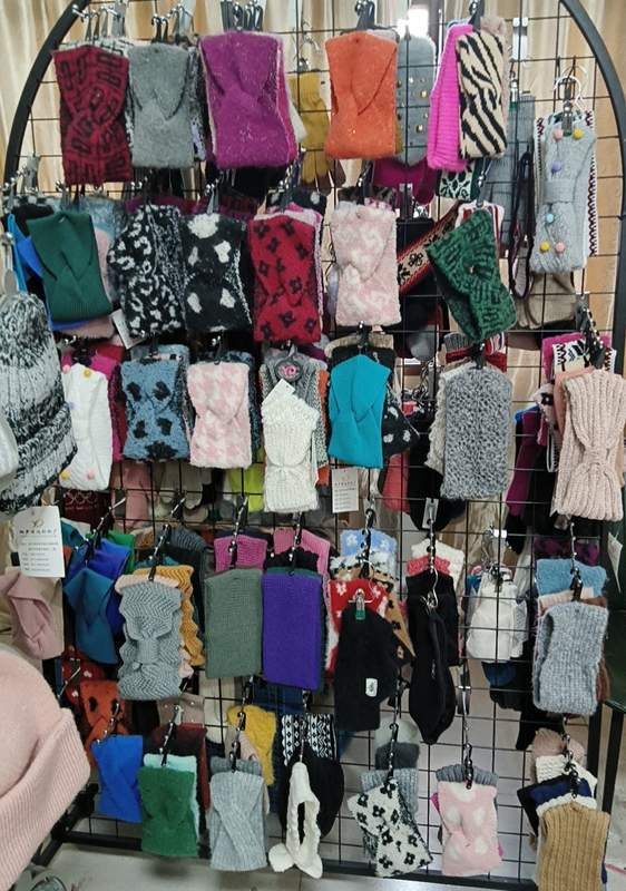 Large retail display rack featuring dozens of knitted fingerless gloves and mittens in various colors, patterns, and textures for winter - factory direct price no middleman