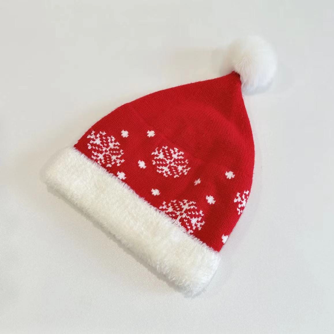 Red knitted Christmas Santa hat with white snowflake pattern, plush white brim, and fluffy pom-pom on white background - low MOQ 50pcs trial order