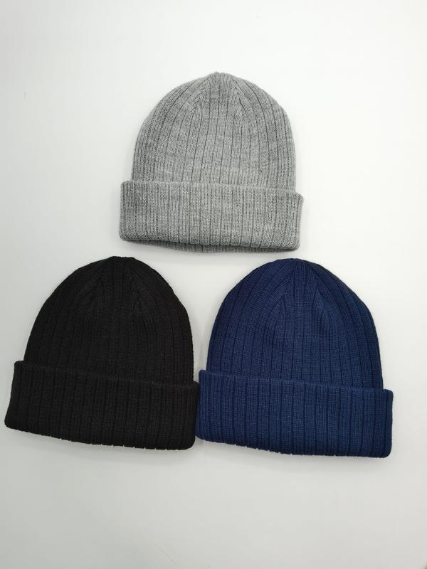Three ribbed knit cuffed beanie hats laid flat in light grey, black, and navy blue on white background - EU REACH compliant material