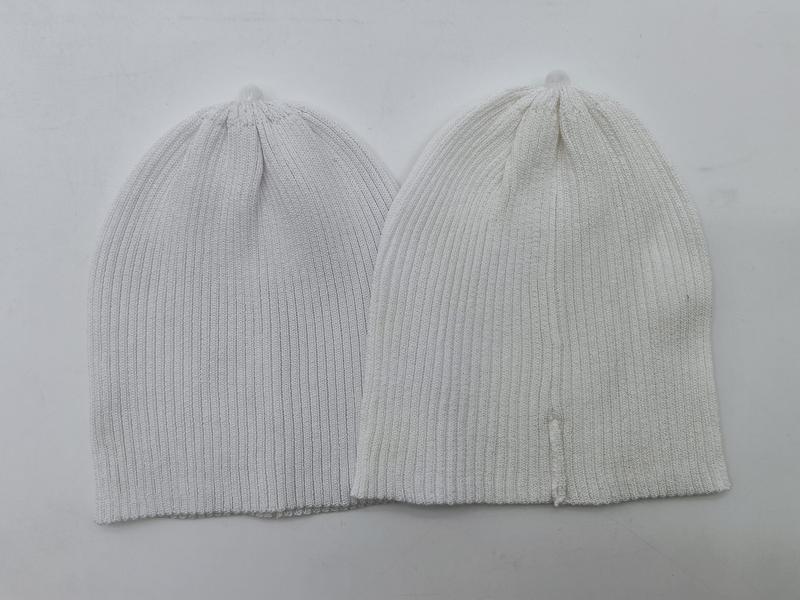 Two ribbed knit beanie hats laid flat, one light gray and one off-white, showing fine rib texture and slouchy fit - air shipping 5-7 days arrival