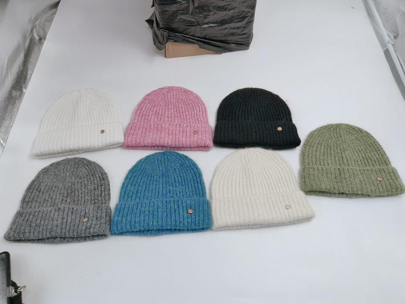 Seven ribbed knit beanies in white, pink, dark green, sage, gray, blue, and cream laid flat on white surface - ODM OEM service available - ISO 9001 quality controlled