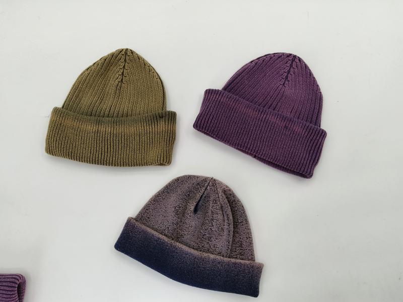 Three ribbed knit beanie hats laid flat in olive green, dusty purple, and two-tone gray-navy colorways - BSCI + Oeko-Tex + GRS certified