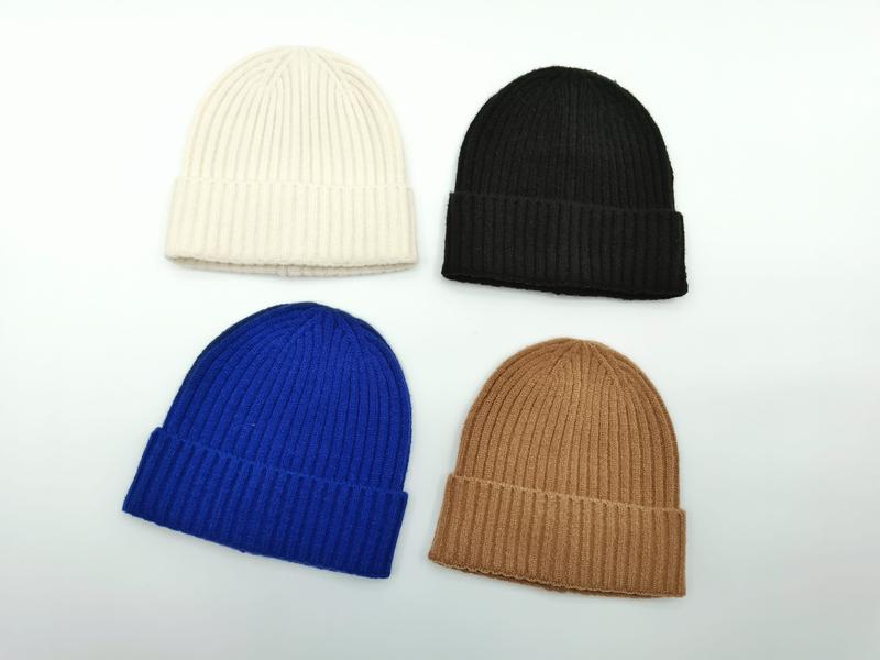 Four ribbed knit cuffed beanies in cream, black, cobalt blue, and camel arranged on white background - wholesale price for USA buyers