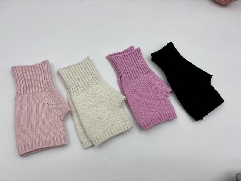 Four ribbed knit fingerless gloves in pink, cream, lilac, and black laid flat on white surface - EU REACH compliant material
