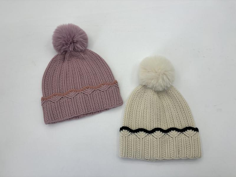 Two ribbed knit pom-pom beanies laid flat: dusty pink with rust scallop trim and cream with black scallop trim, each with faux fur pompom - tiered pricing available ask quote