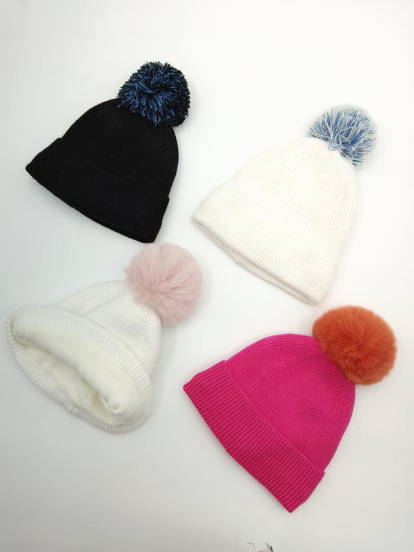 Four ribbed knit winter beanies with colorful pom poms in black, white, and fuchsia pink laid flat on white background - jacquard custom pattern accepted