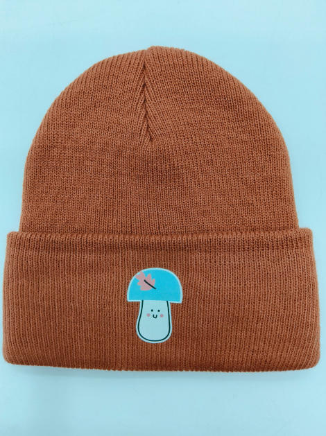 Rust brown ribbed knit cuffed beanie hat featuring a kawaii blue mushroom character patch on the fold - wholesale price for Middle East buyers