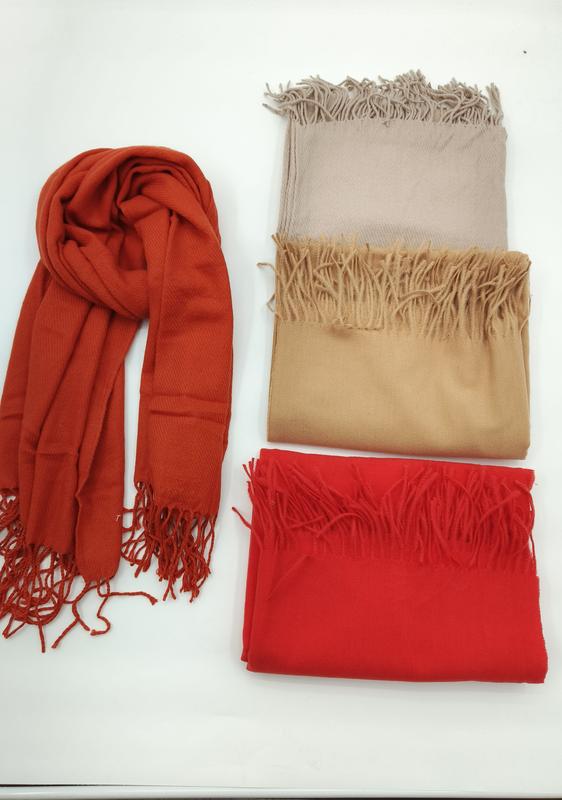 Four pashmina scarves with fringe in rust orange, light beige, camel, and red, one draped and three folded on white surface - email us get price list now