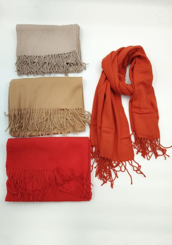 Four solid color pashmina-style scarves with fringe in beige, camel, red, and burnt orange, one draped and three folded - WhatsApp quote in 2 hours