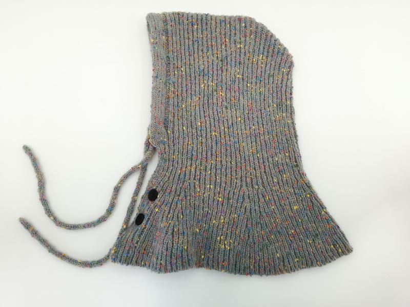 Flat lay of a gray multicolor speckled knit baby bonnet with chin ties and two black snap buttons on white background - certified scarf manufacturer China