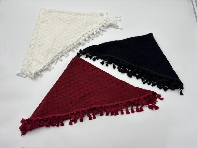 Three triangle knit shawls with tassel fringe in cream, black, and burgundy laid flat on white background - boutique retail bulk order