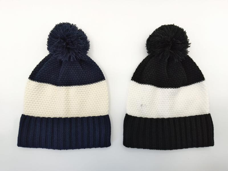 Two knit pom-pom beanies side by side: navy blue and cream stripe on left, black and cream stripe on right, on white background - factory direct price no middleman