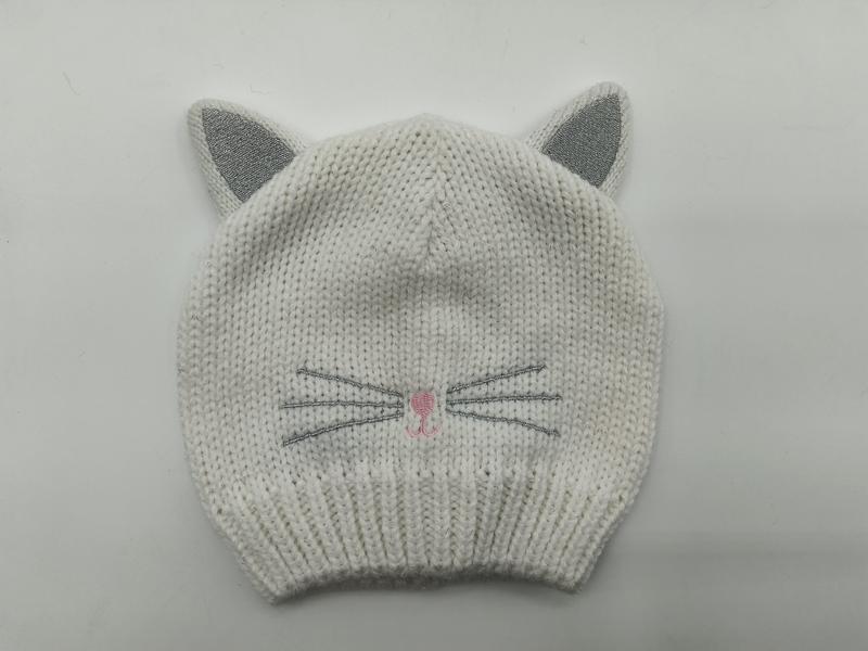 White chunky knit baby beanie hat with silver glitter cat ears, embroidered whiskers and pink nose detail on gray background - winter accessories wholesaler