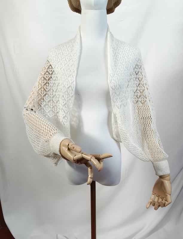 White open-weave lace knit cropped bolero shrug with long balloon sleeves and ribbed cuffs on a mannequin - wholesale price for Europe buyers