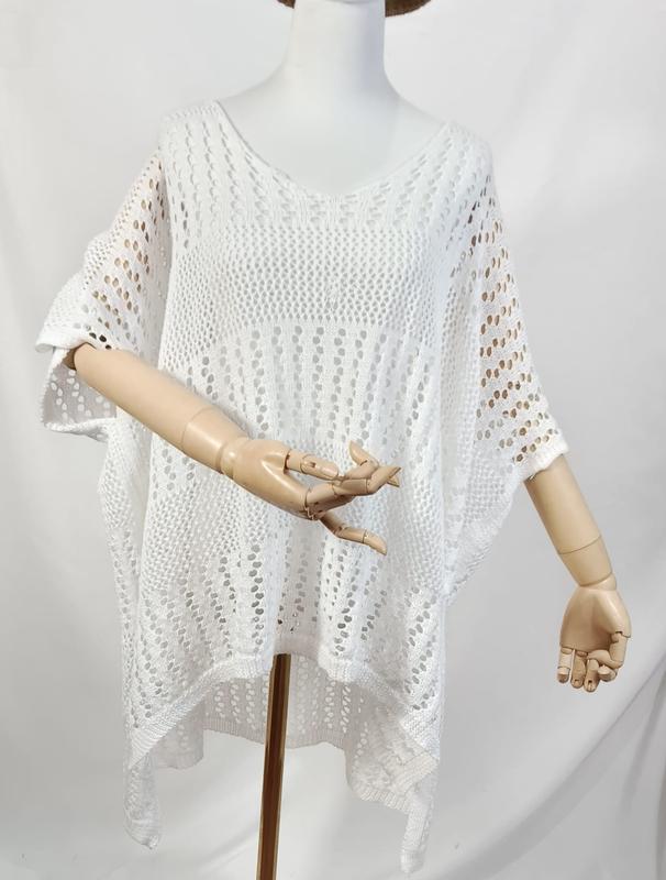 White oversized open-knit crochet poncho top with V-neck and short sleeves displayed on a mannequin with wooden hands - event merchandise supplier